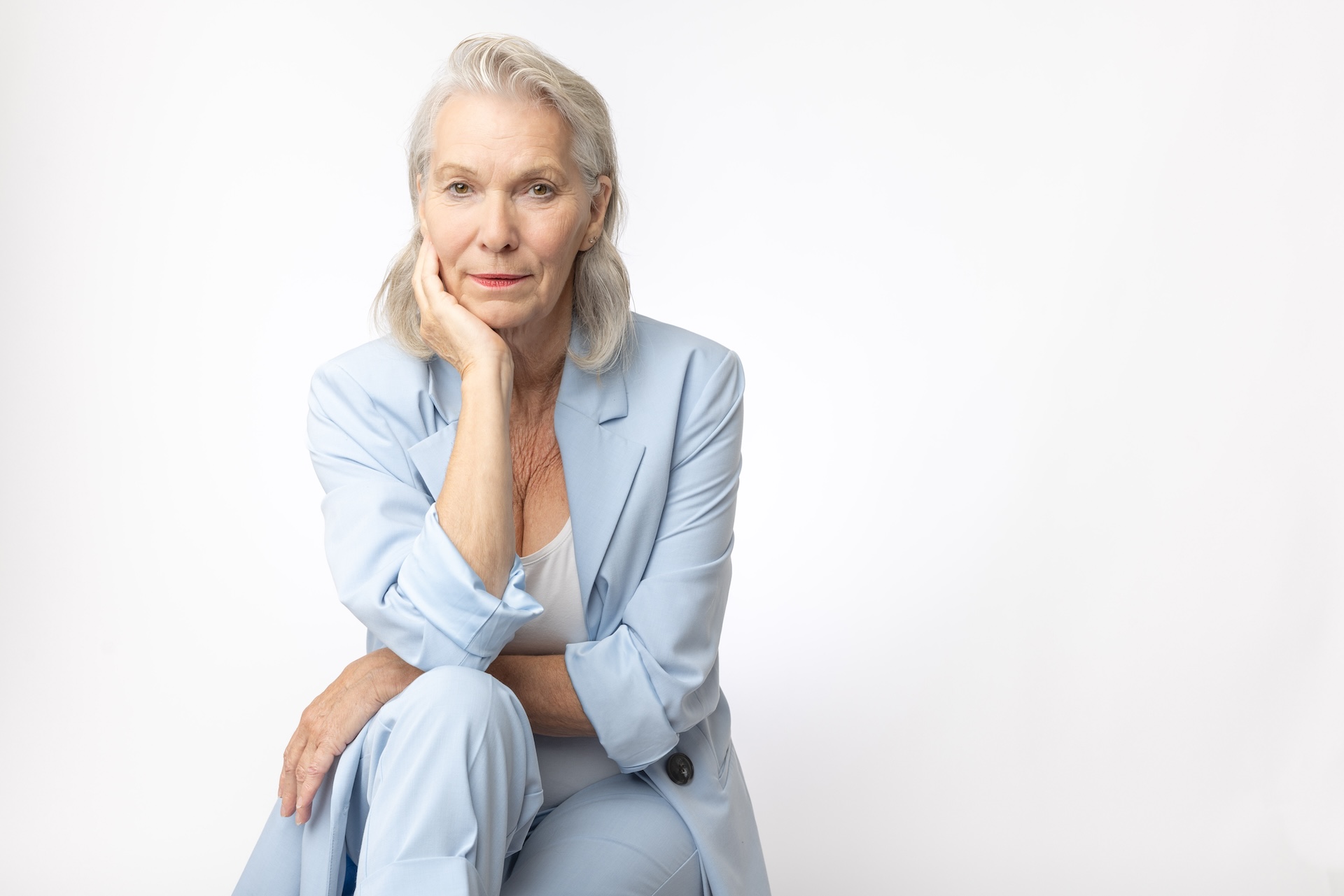Kvinne 73 år i lyseblå dress, uredd og direkte i blikket, proppfull av selvtillit
