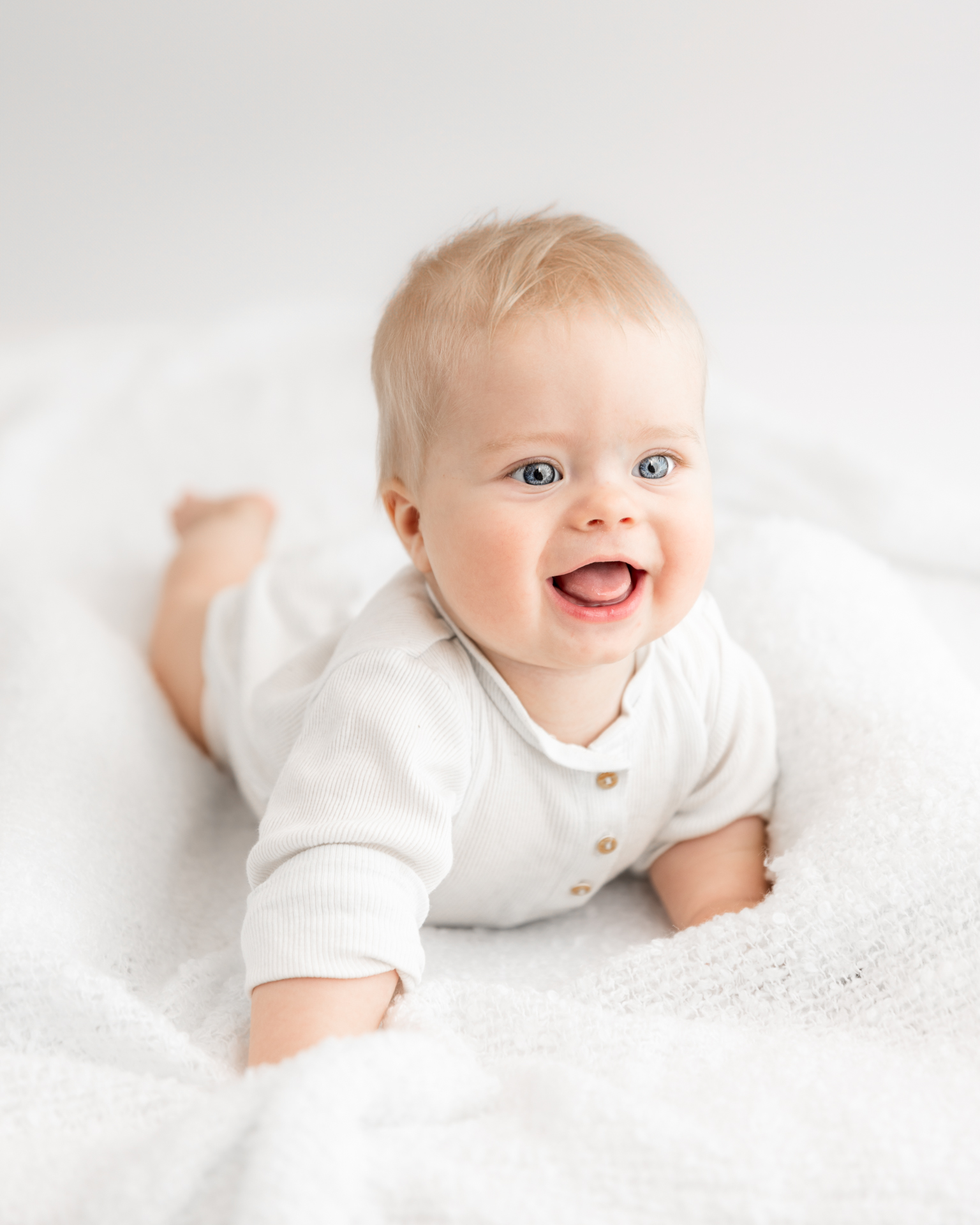 Portrett av gutt på 7 måneder som ler og ser ut i rommet